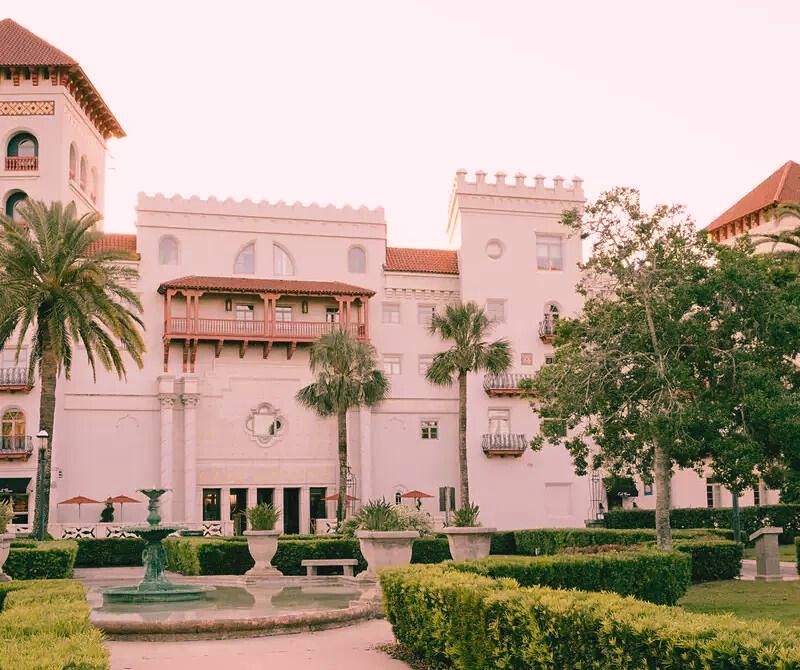 One of the most haunted places in Florida, The Casa Monica Hotel, a grand white structure with palm trees and a fountain, famous for its history.