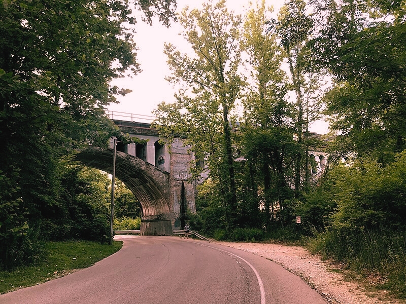 The Avon Haunted Bridge, a historic structure from 1906, looms over a road, framed by trees and steeped in ghostly lore.
