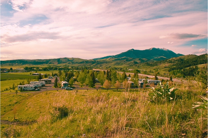 An RV park nestled in a forest with mountains in the background, showcasing Montana's natural beauty and eerie atmosphere.