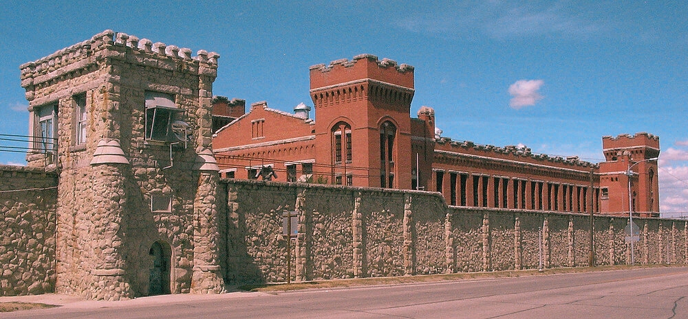 The Old Montana State Prison, a large brick structure with a tower, built in 1871, notorious for housing dangerous inmates.
