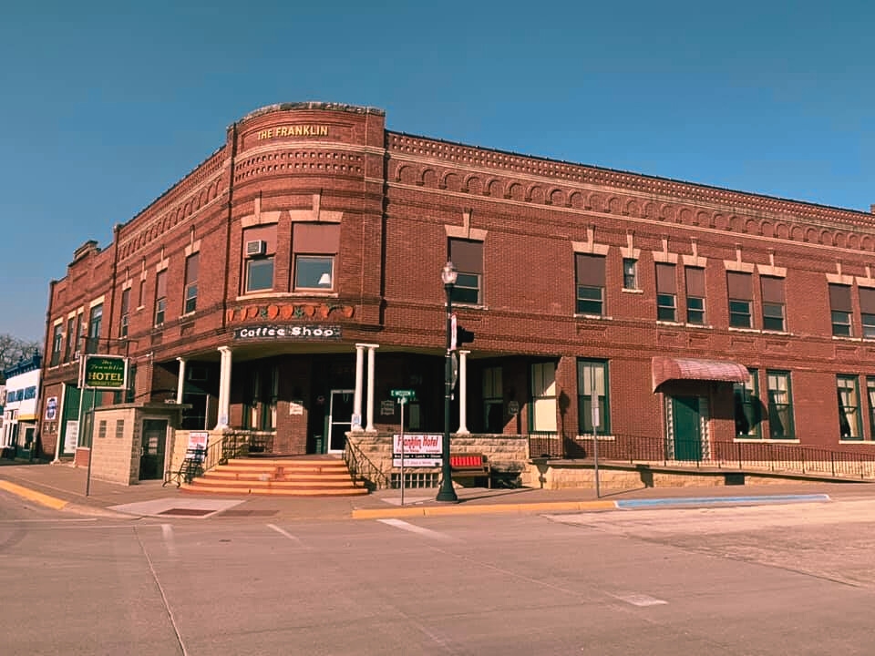The Franklin Hotel, a historic brick building located on a street corner in Strawberry Point, Iowa.