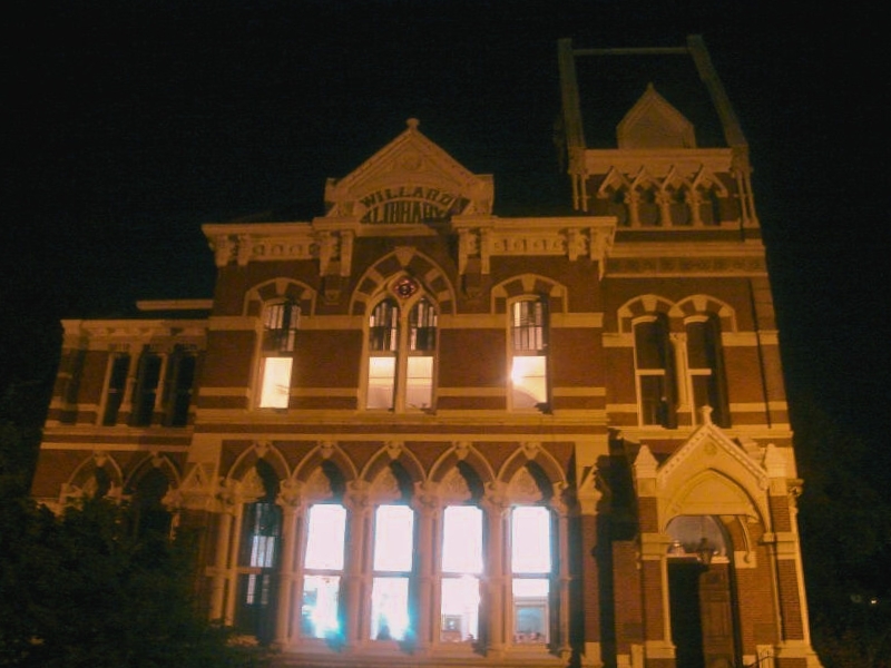 A large building with a clock tower illuminated at night, symbolizing Willard Library's rich history and community service.