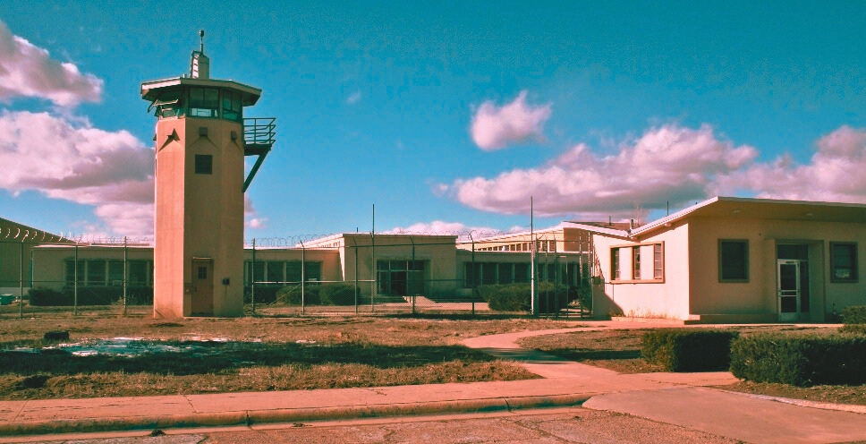 One of the most haunted places in New Mexico, the historic Old Main Prison, enclosed by a fence.