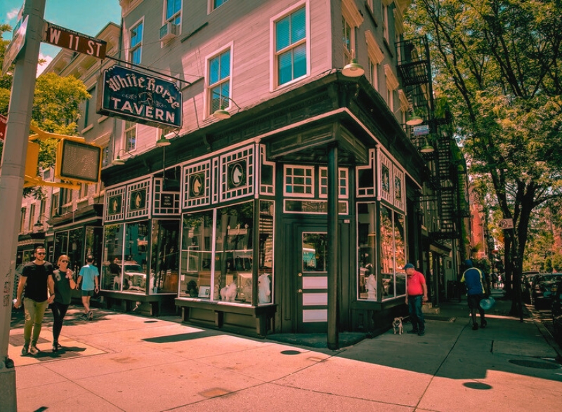 People stroll past one of the most haunted places in New York City, the iconic White Horse Tavern on a lively street corner in Greenwich Village.