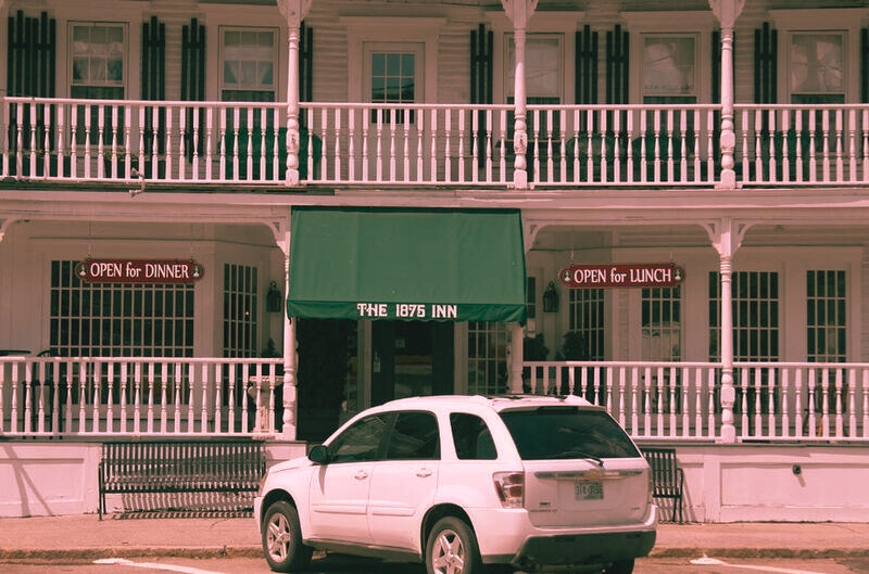 A white car is stationed outside The Tilton Inn, a historic landmark from 1875, notable for its rich history and charm.