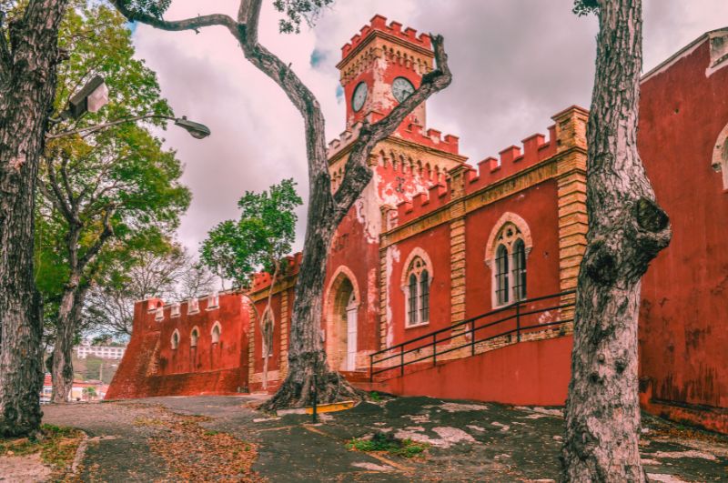 Fort Christian, a red brick structure enveloped by trees, recognized as one of the haunted places in the U.S. Virgin Islands.