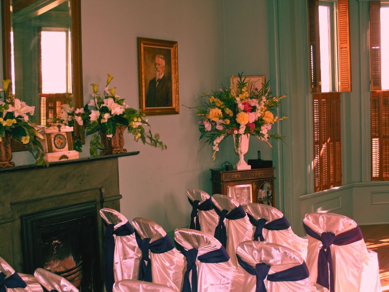A cozy room in The Clayton House featuring chairs, flowers, and a fireplace, evoking a haunted atmosphere.